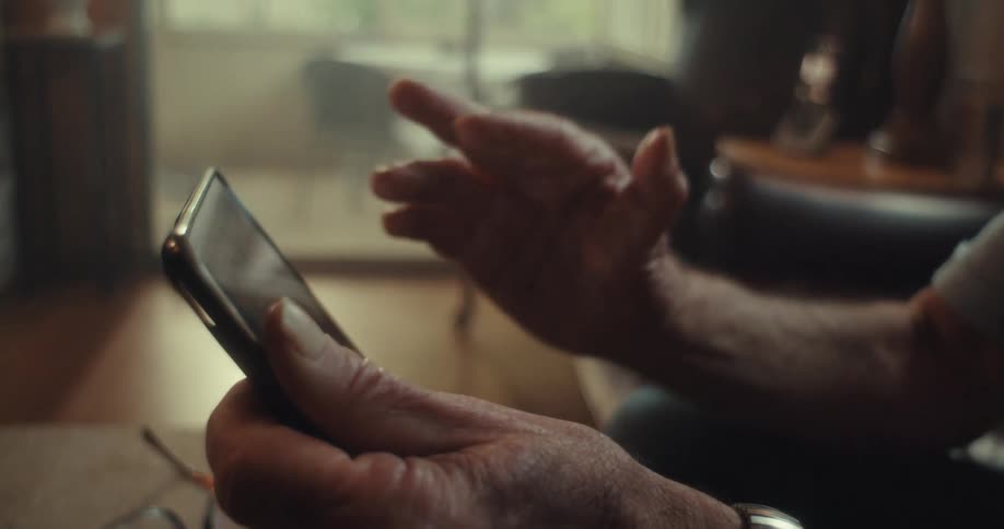 Elderly man watching something on his smartphone and smiling
