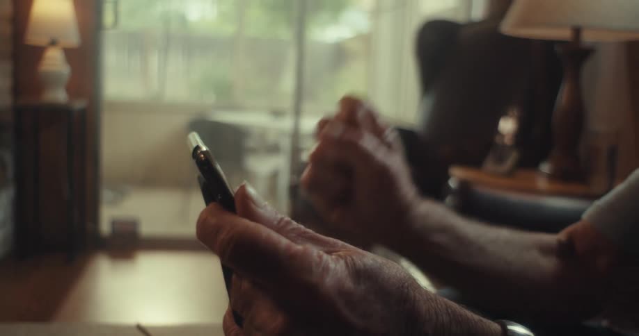 Elderly man using a tablet looking at it and waving with a smile