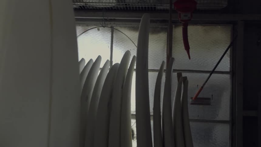 Unfinished surfboards are stacked against a frosty window