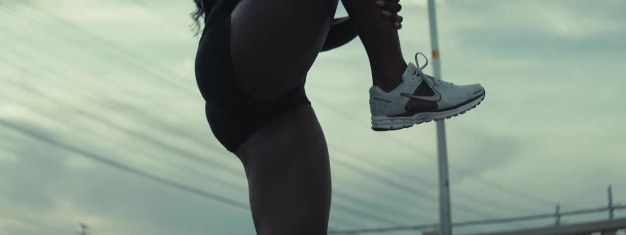 Woman in sportswear holds one leg while stretching outdoors