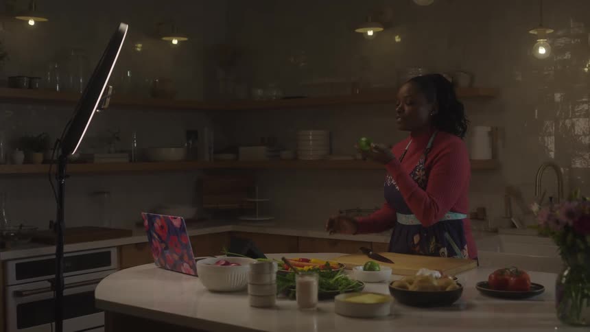 A woman records a video of herself in the kitchen