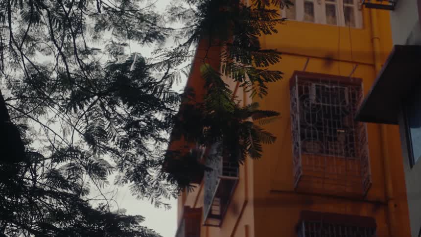 Metal bars cover the windows of an orange apartment building on a cloudy summer day