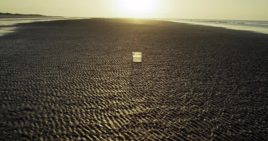 Outdoor video screen stands on the textured sand of a beach at sunrise