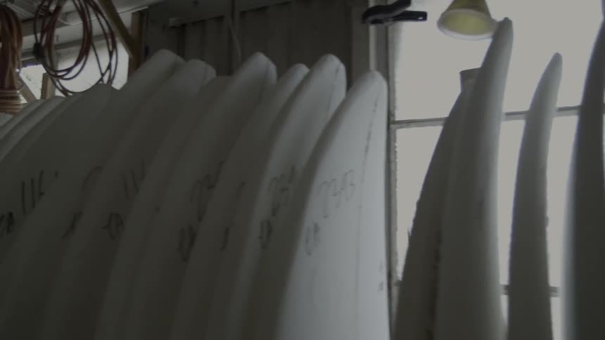 White surfboards lined up against a wall