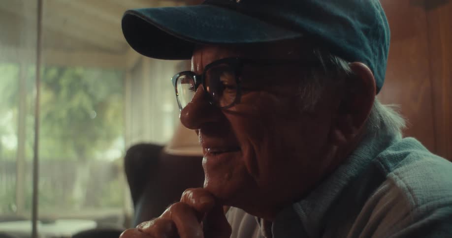An elderly man is looking at his phone and smiling