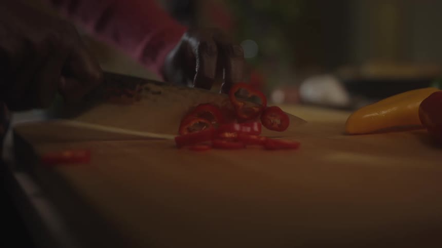 Close up of a black woman slicing a red pepper with a knife