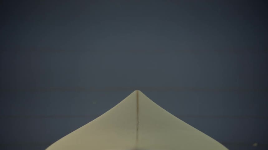 An unfinished surfboard rests on two posts in a workshop