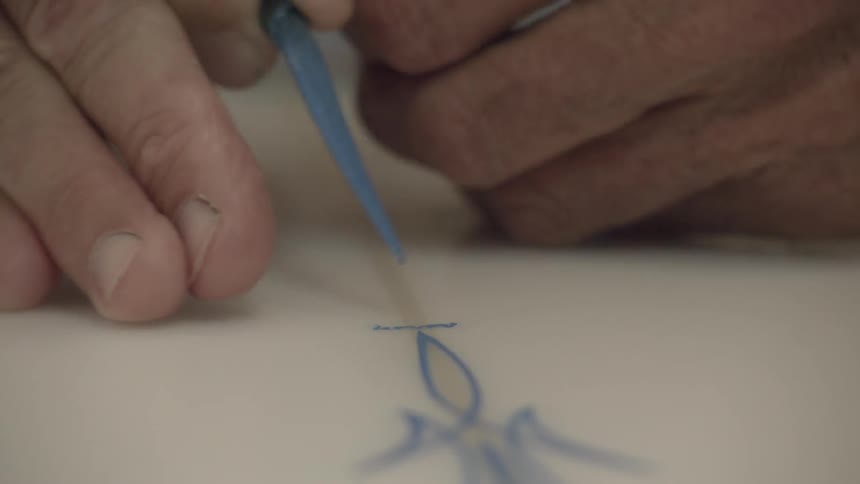 A man is using a brush to paint a design on a surfboard