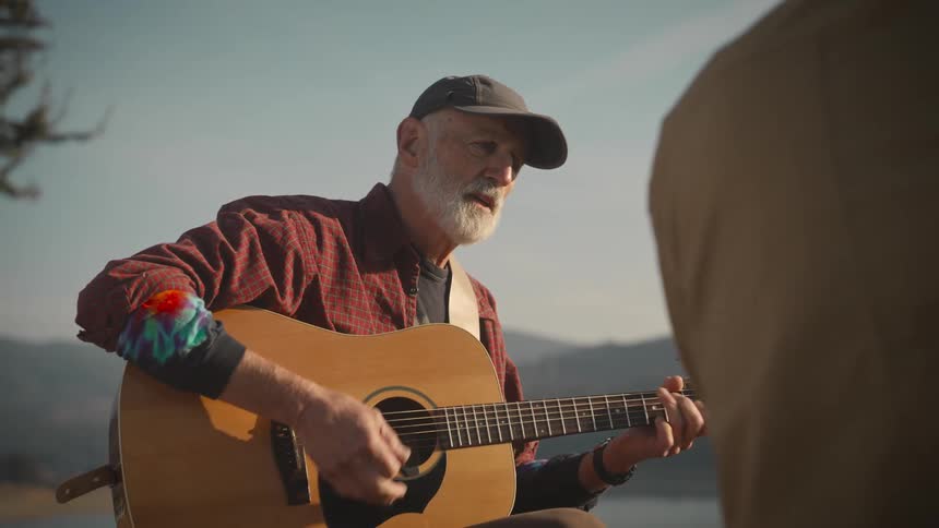 A man plays a guitar and sings