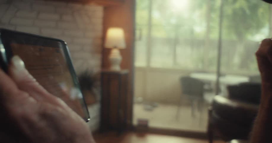 Elderly man is laughing and looking at a tablet