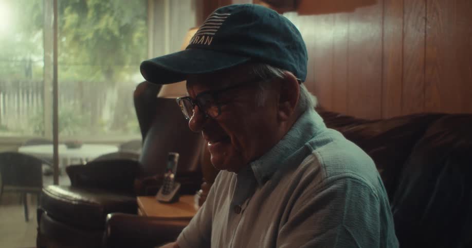 Elderly man sitting on a sofa celebrating happily watching on tablet
