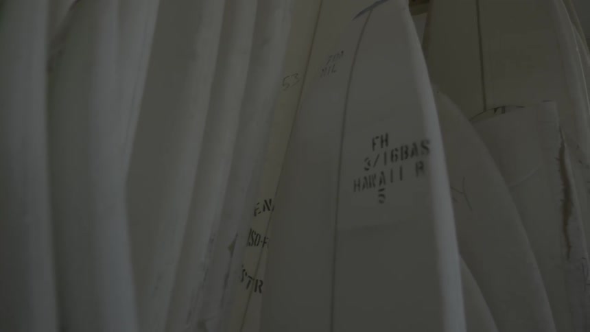 The wall is lined with many surfboards