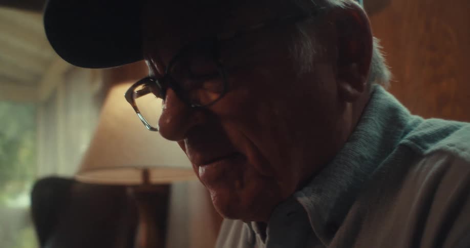 Older man wearing a war veteran hat sitting on the living room couch