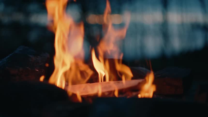 Firewood being thrown onto a bonfire in the late afternoon