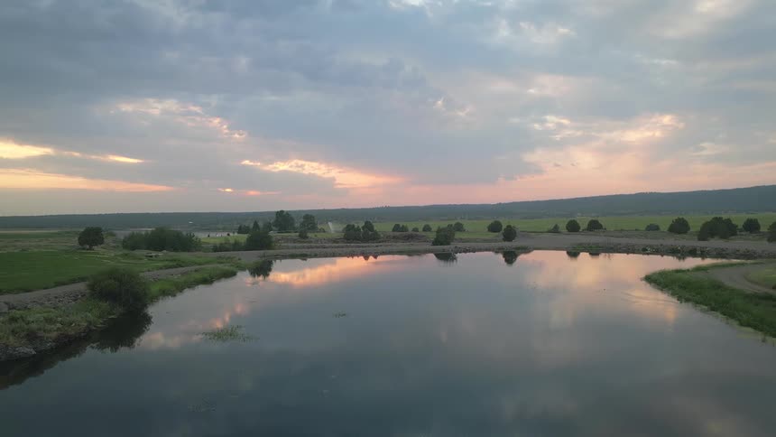 Scene of a pond in a green environment with mountains on the horizon