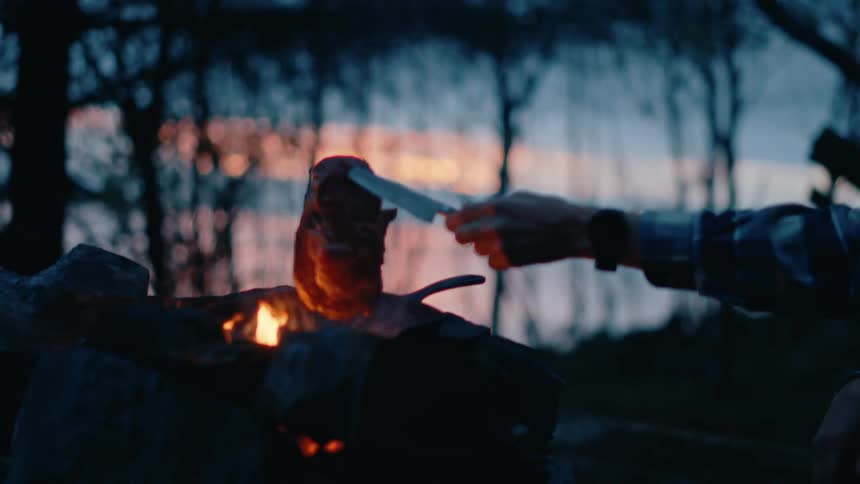 Meat being grilled on an outdoor fire pit