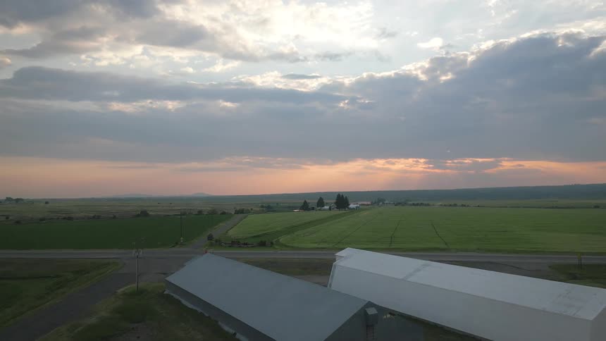Aerial view of an agricultural field at sunrise and two potato cellars