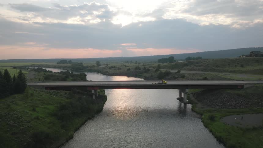 Narrow river surrounded by vegetation and a bridge in the background