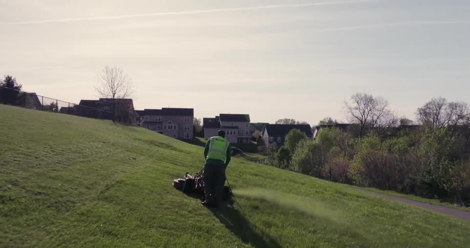 Overhead view of a man mowing a lawn with a mobile machine