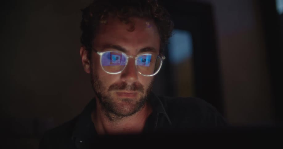 Closeup of a man looking into a computer screen as he scrolls through