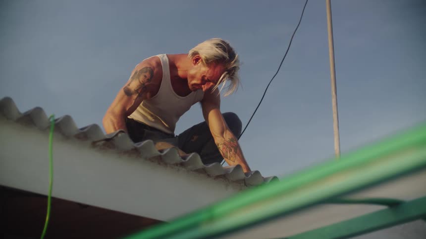 Man with hammer working on top of a roof