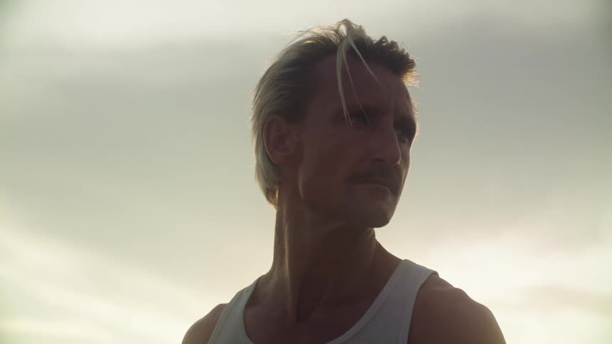 Blonde man looking to the side while standing in an outdoor setting