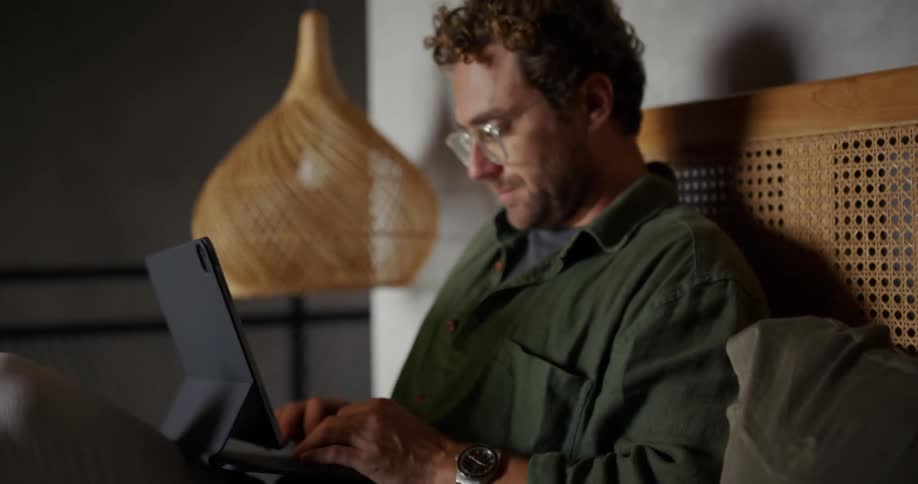 Man looking at a notebook and typing on a laptop