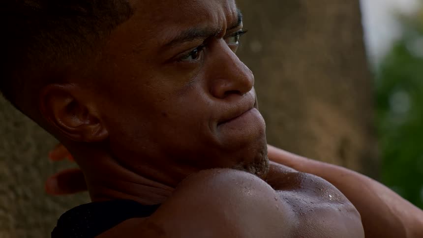 Close up of a black man stretching outdoors during the day