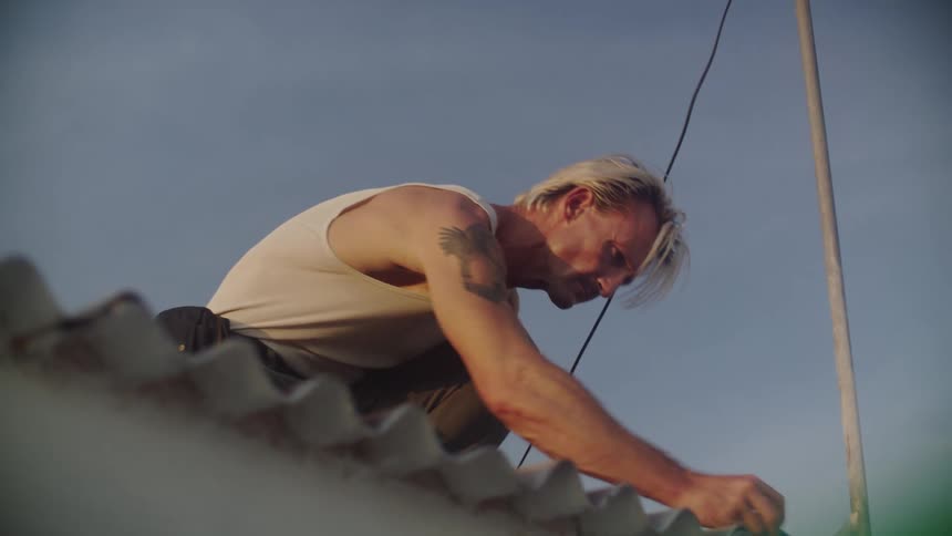 Blond man in a tank top on a roof