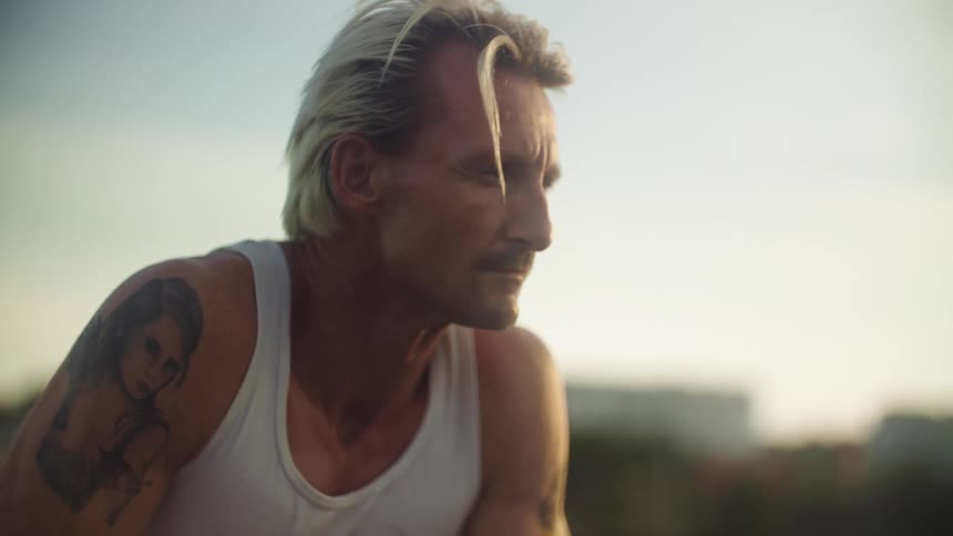Blond man in tank top outdoors looking thoughtful