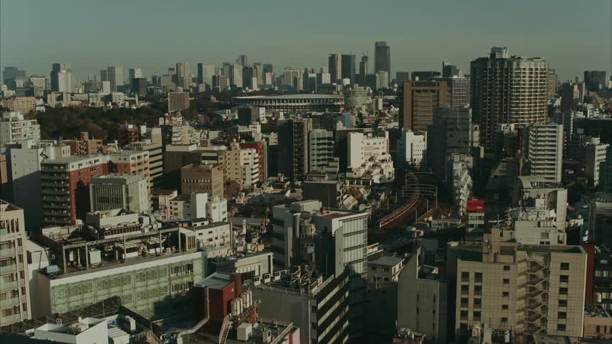 Panorama of a modern metropolis with a train passing through the middle of the city and a stadium in the background