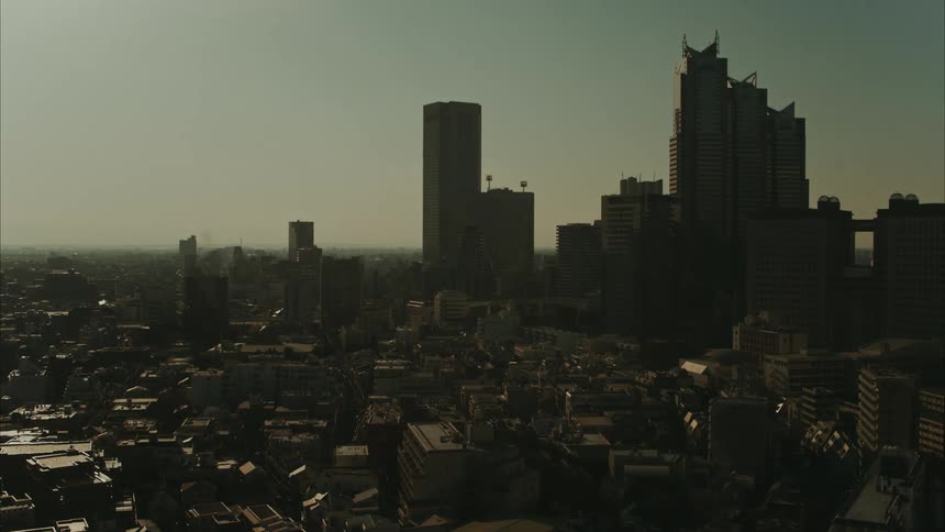 Tall downtown skyscrapers tower over the surrounding buildings and stand partially silhouetted against the sky after dusk