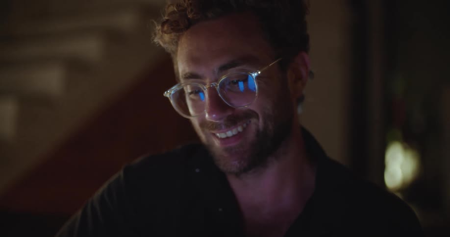 Smiling man in glasses typing on a smartphone and holding a guitar