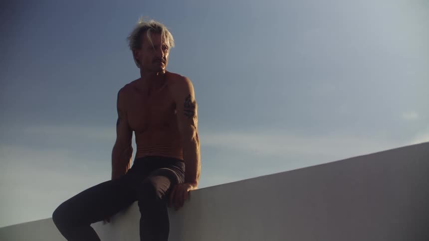 Shirtless man sitting outdoors and leaving the place
