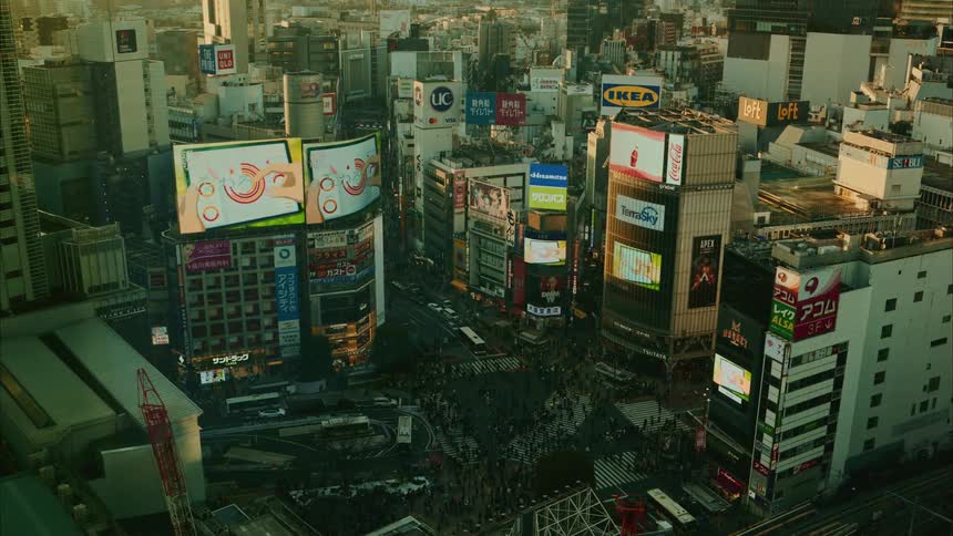 A highangle view showcases the busy shibuya crossing in tokyo with dense pedestrian traffic and surrounding buildings featuring large advertisements