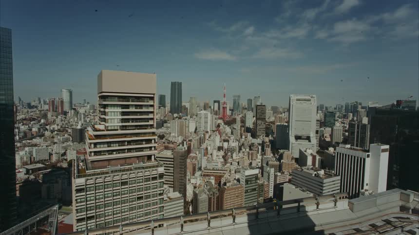 A highangle wide shot of a dense modern city skyline with mid and highrise buildings under a clear blue sky