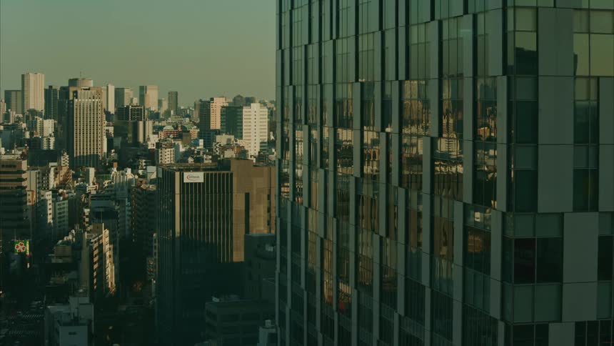 A partial view of a modern skyscraper with numerous windows dominates the right side of the frame overlooking a dense urban landscape under a muted sky