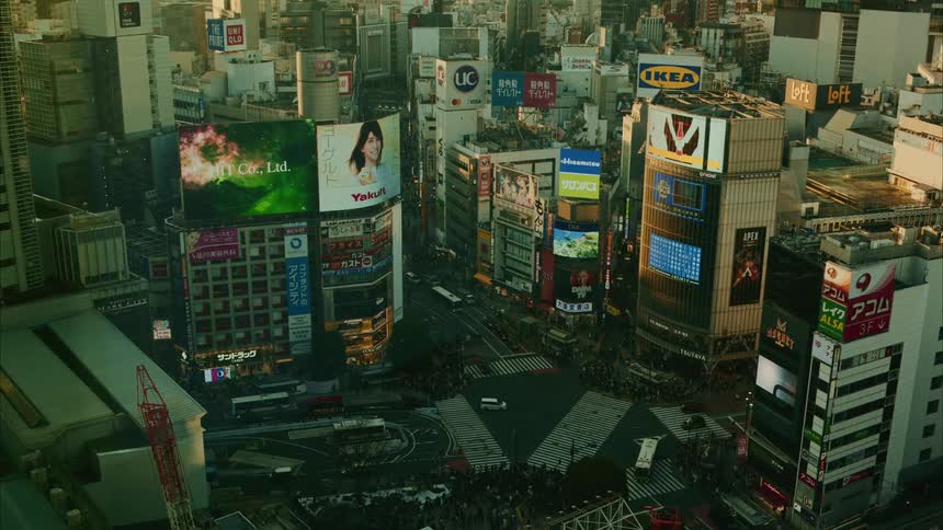 Busy city center with many cars and buses and tall buildings featuring large advertising screens