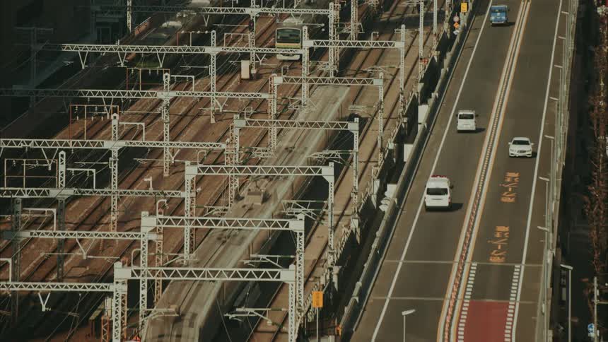 Highway with vehicle traffic next to tracks with trains passing by