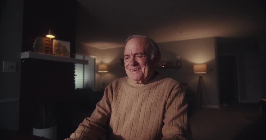 Elderly man sitting in front of laptop smiling