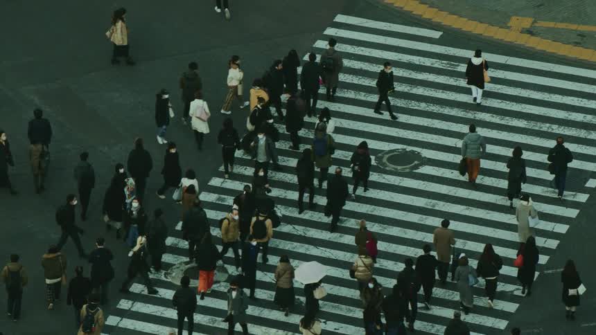 Several pedestrians cross the street at a crosswalk