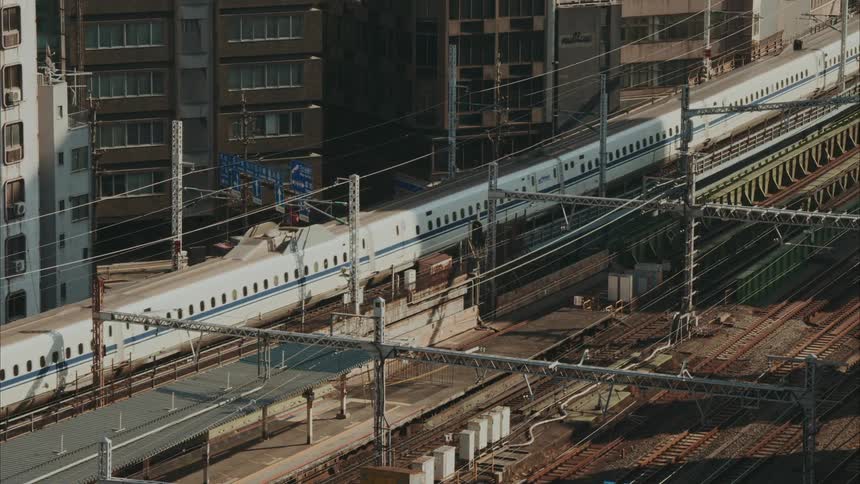 A highspeed train is traveling through an urban area surrounded by tall buildings and electrical infrastructure