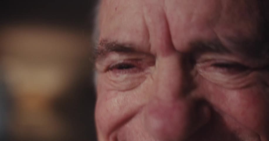 Elderly man laughs pleased by what he is watching