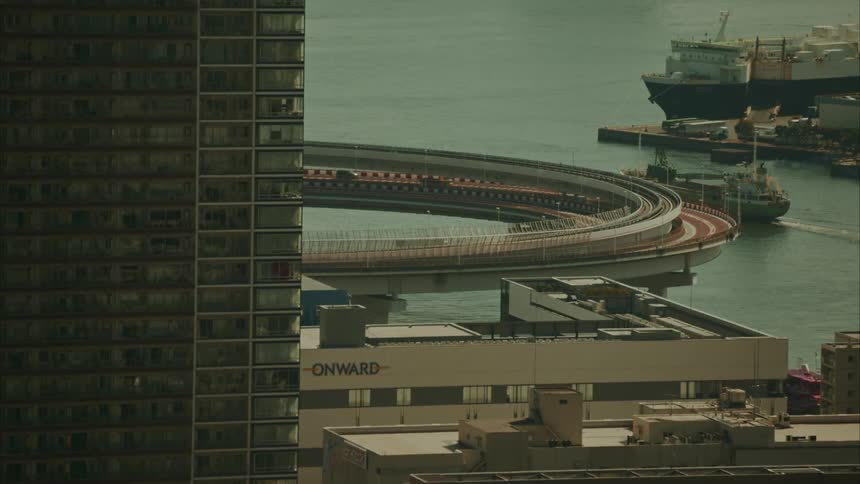 Buildings of metropolises in the foreground and in the background a viaduct on a bridge over the sea with ships
