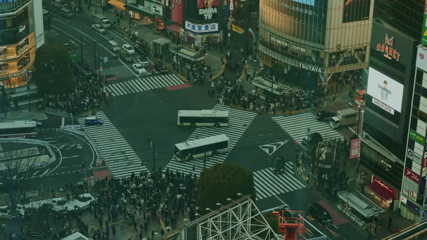 View from above of an intersection with thousands of pedestrians and vehicle traffic in a metropolis