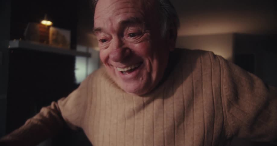 Cheerful elderly man sitting in front of a laptop