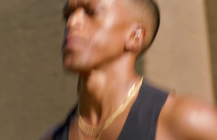Man wearing a muscle shirt jogs past a building on a summer day