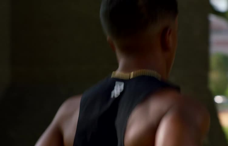 Back view of a man in a black tank top running outdoors