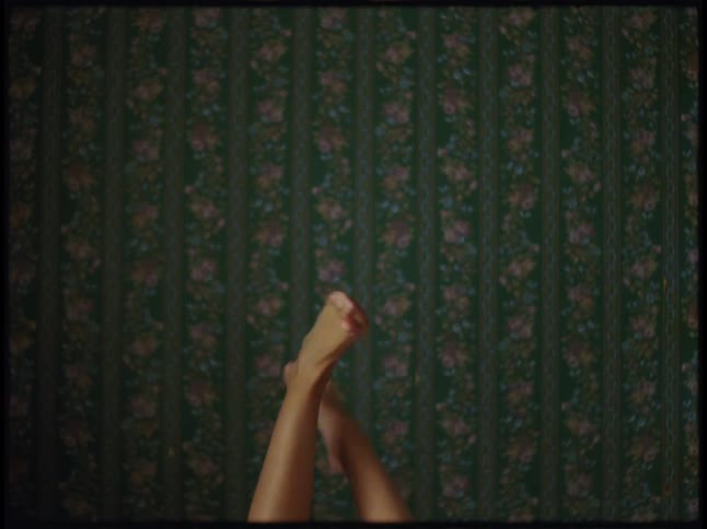 Two bare legs playfully twist above a richly patterned vintagestyle carpet viewed from directly overhead