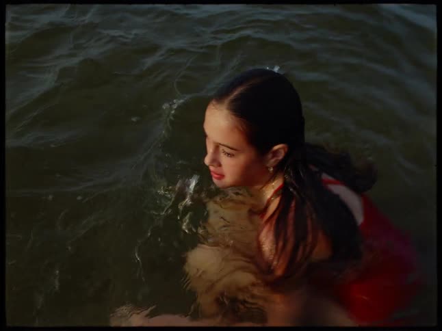 A young woman swims and dives playfully in a large body of water during daylight